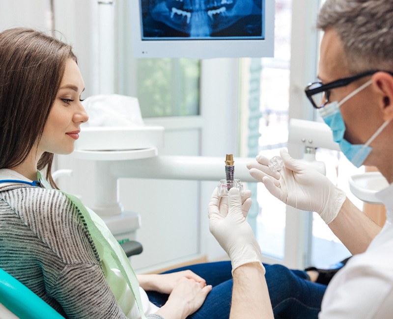 Dentist showing large sample implant to patient