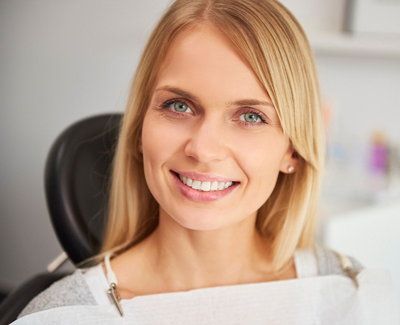 Female dental patient sitting in chair smiling