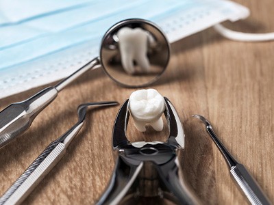 Forceps holding a tooth lying next to other dental instruments