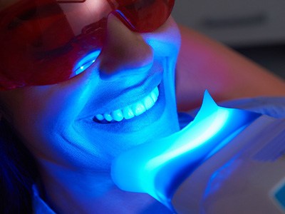 Woman undergoing teeth whitening procedure with light