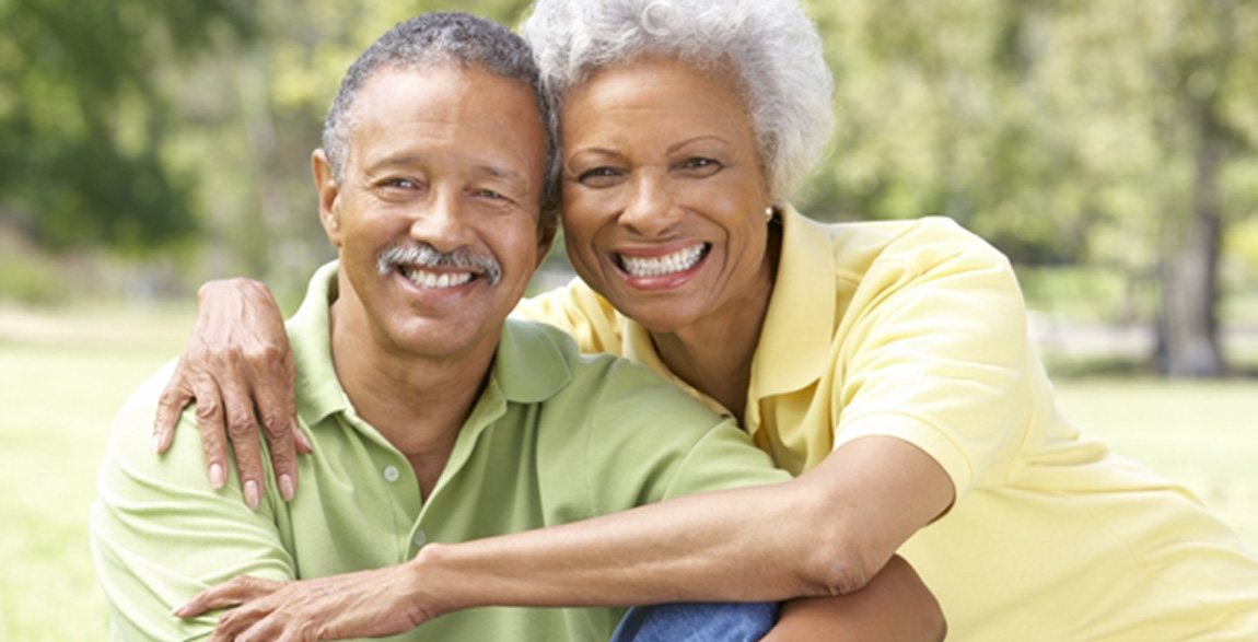 Older couple smiling with dental crowns in Rochester  