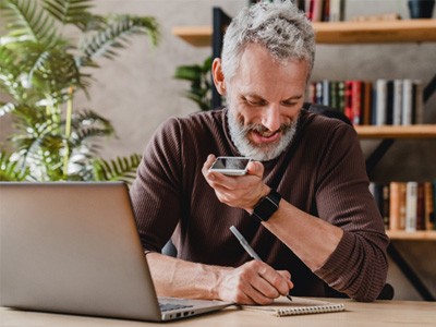 A senior man talking by speaker phone in his workspace