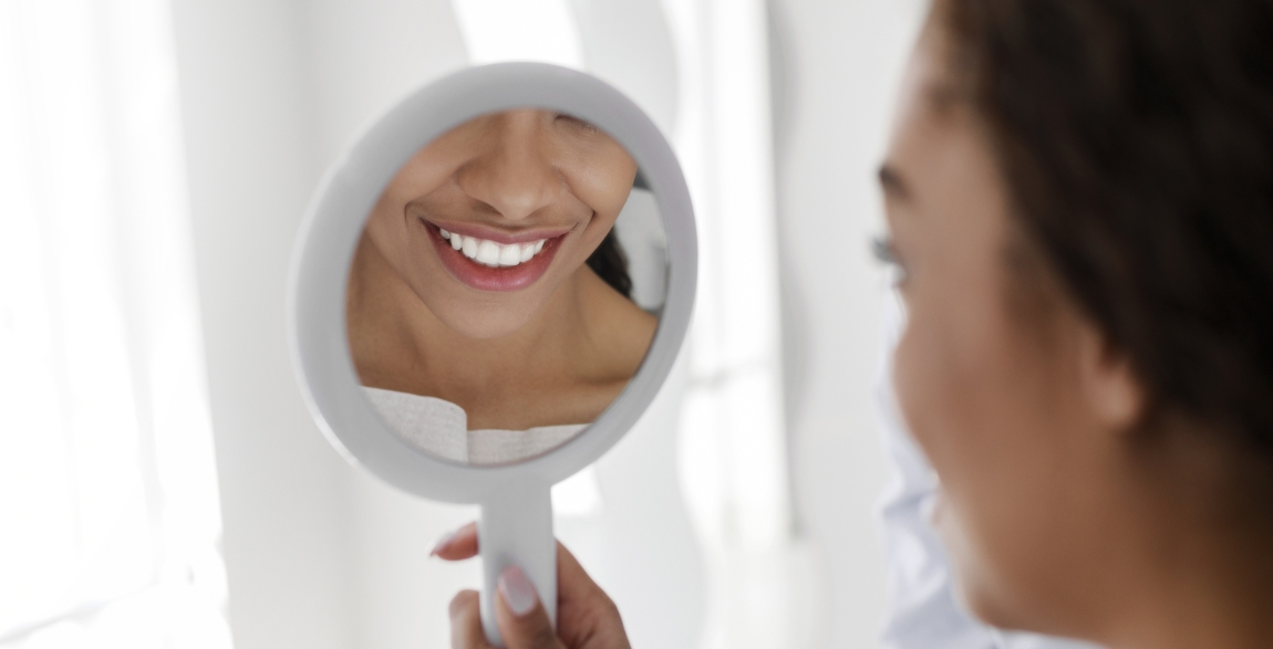 Woman looking at smile after dental checkup and teeth cleaning visit