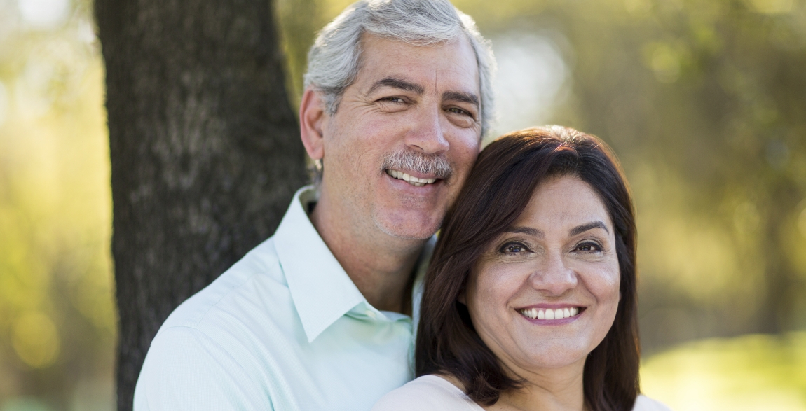 Man and woman smiling after replacing missing teeth with dental implants