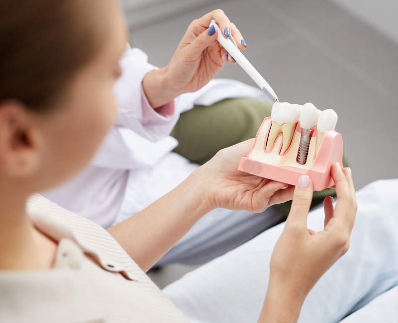 Dentist and patient looking at dental implant model