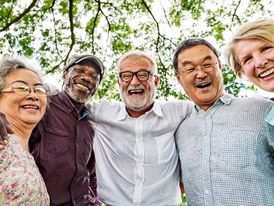 Denture patient in Rochester smiling with their friends