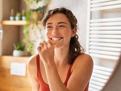 Smiling woman brushing her teeth