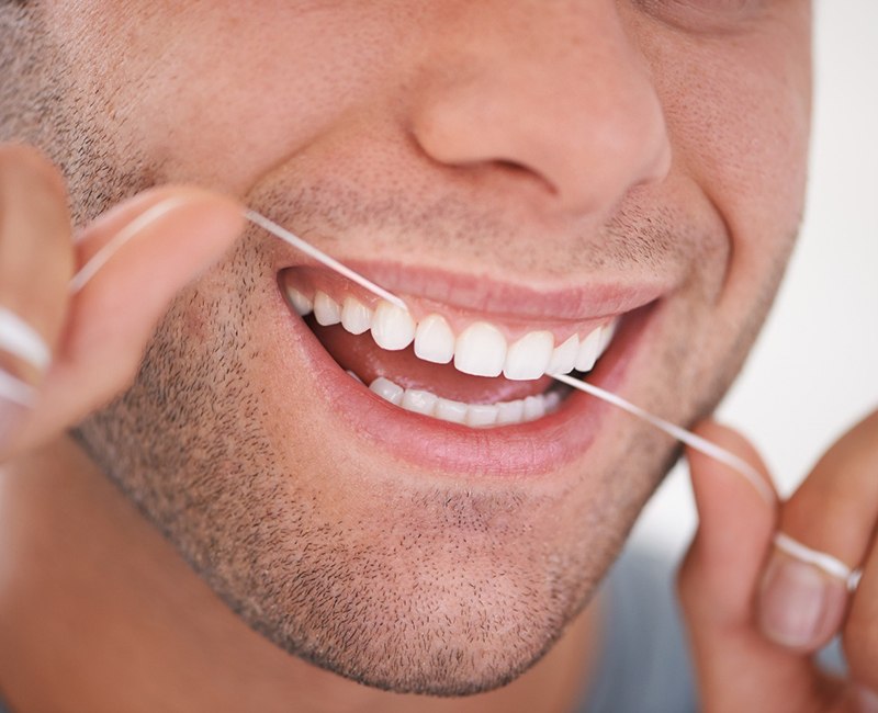 A man flossing his teeth after gum recontouring