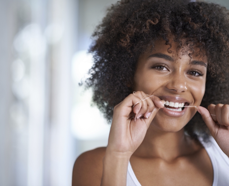 Woman flossing to prevent dental emergencies