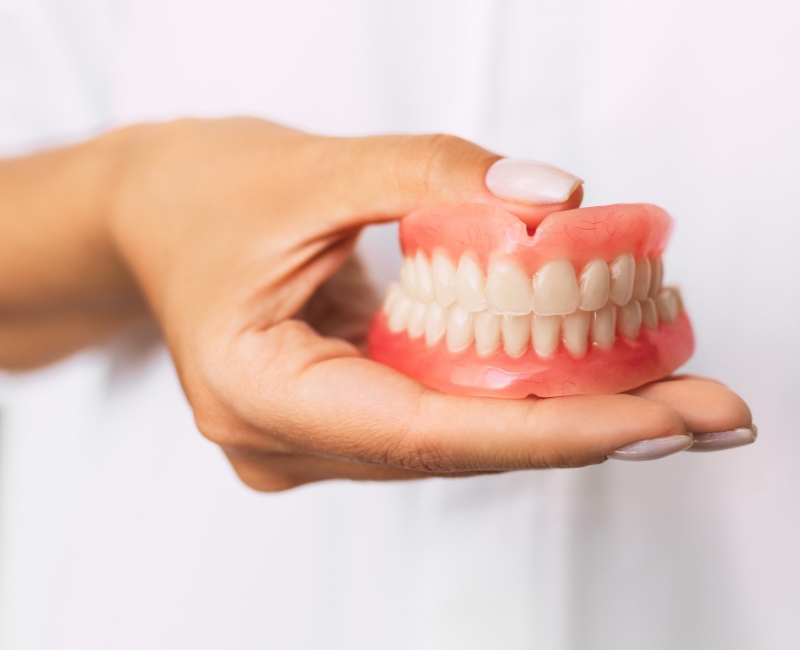 Hand holding full set of dentures