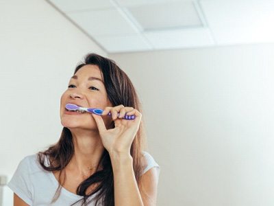 a woman brushing her teeth in the morning