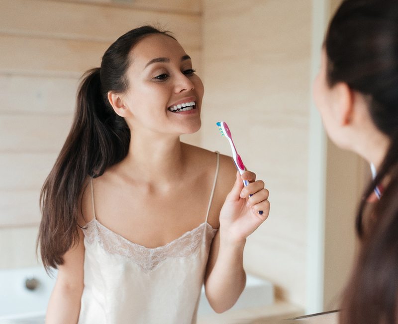 Woman smiling in the mirror with a toothbrush