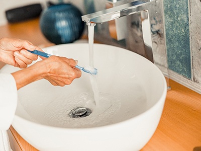 Woman rinsing a toothbrush with water