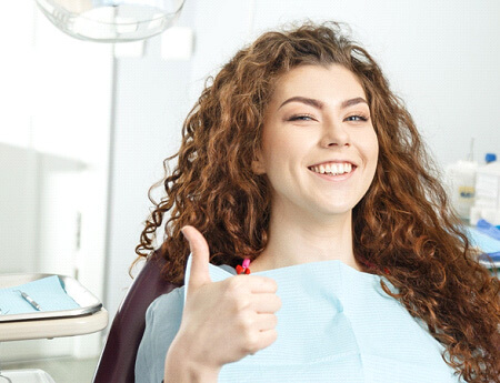 woman in dental chair giving a thumbs up