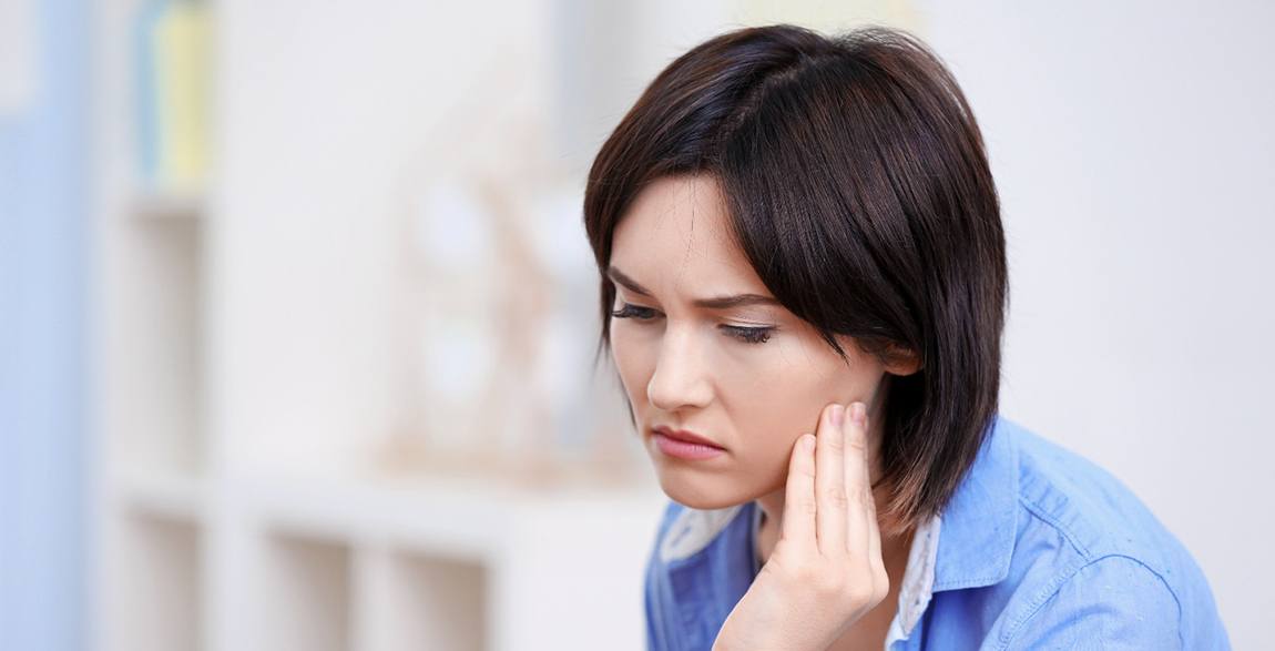 Woman with blue jacket with failed dental implant in Rochester, MN