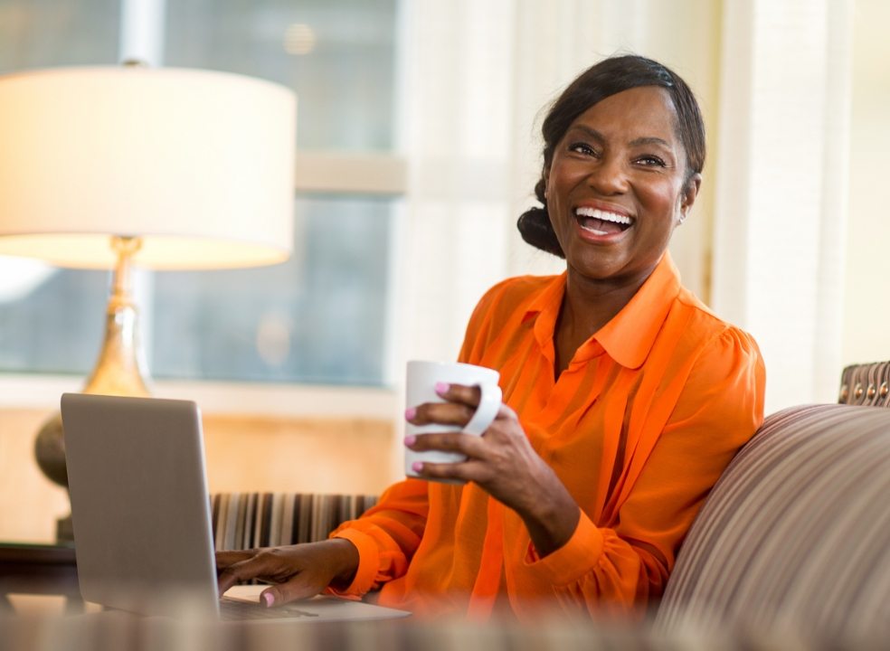 Smiling woman sitting on couch and holding white coffee cup