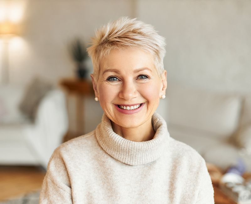 Woman with flawless smile after replacing missing teeth