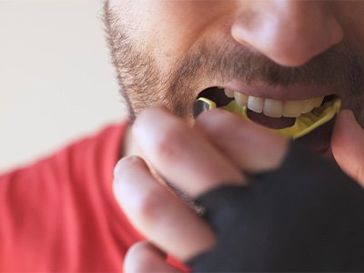 Man in red shirt inserting yellow mouthguard