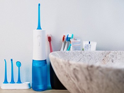 Water flosser and toothbrushes next to a bathroom sink