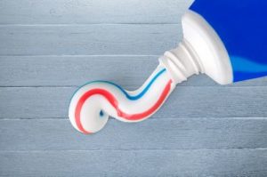 A tube of toothpaste squeezing out a line of paste