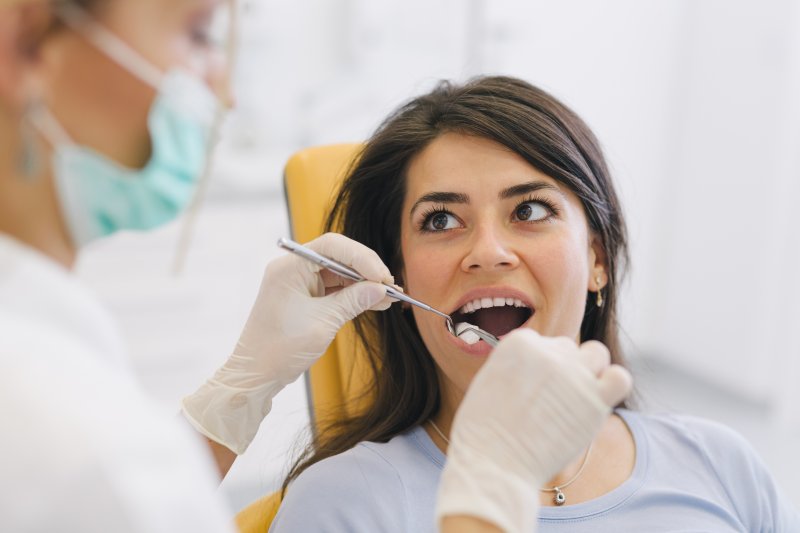 a woman having her teeth and gums looked at by a dentist