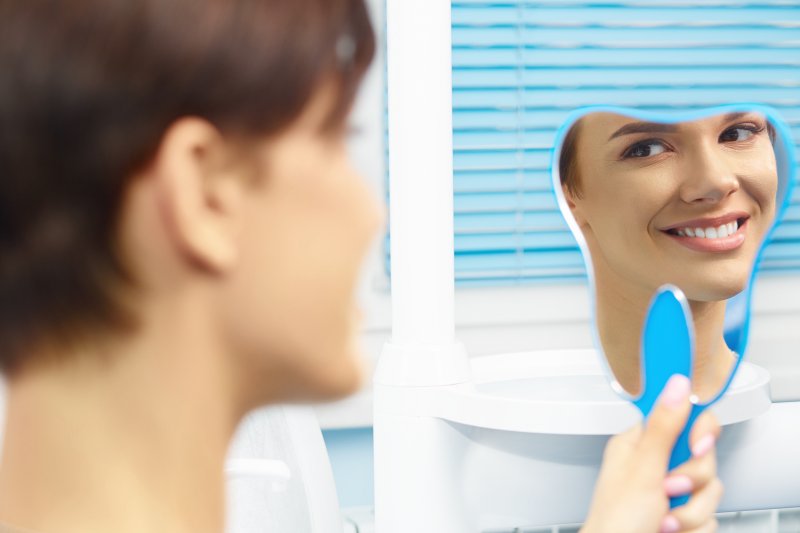 a woman smiling at herself in the mirror at the dentist office 