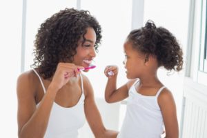 parent and child brushing their teeth together