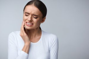 Woman with tooth pain in white shirt