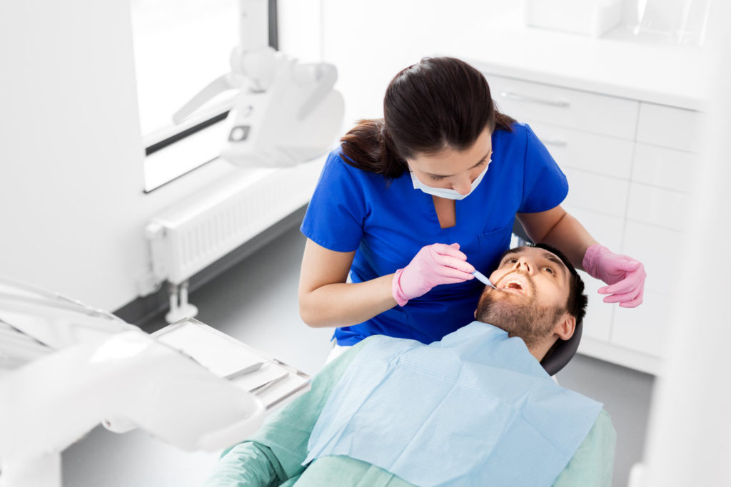 A dentist inspects a mouth for oral cancer