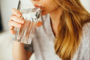 Woman drinking a glass of water after dentist.