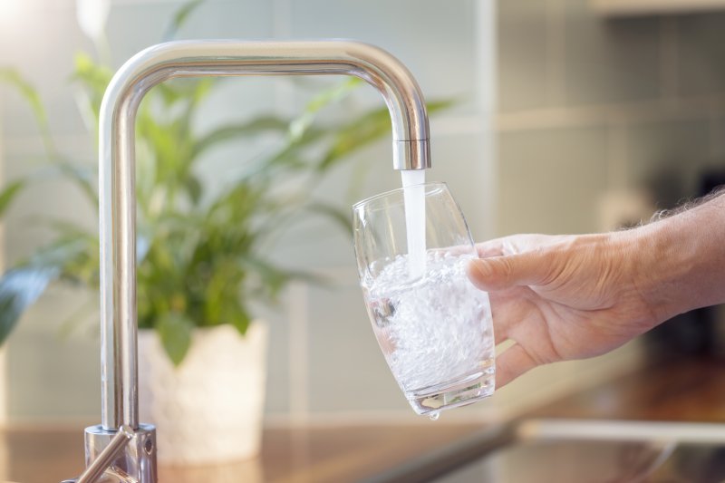 Man filling up glass with water from kitchen faucet