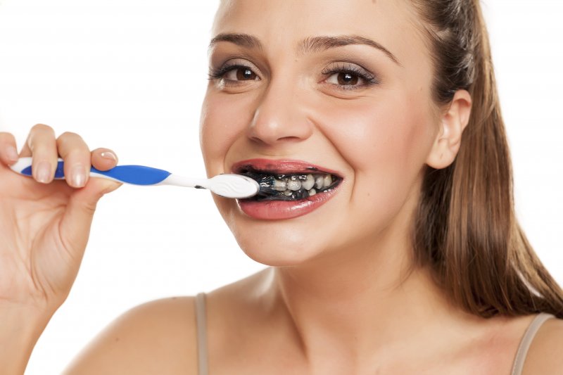 Woman brushing her teeth with activated charcoal