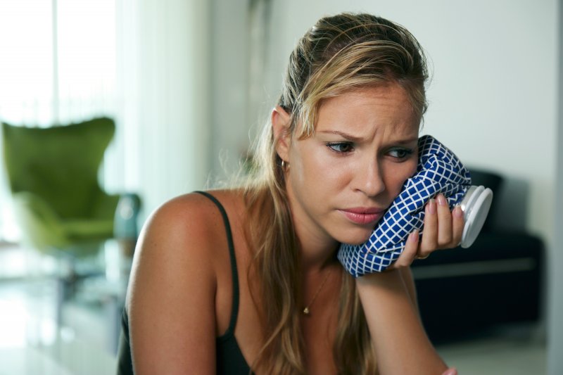 Woman using a cold compress to ease tooth pain