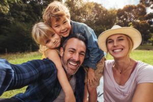 family of four smiling in a forest 