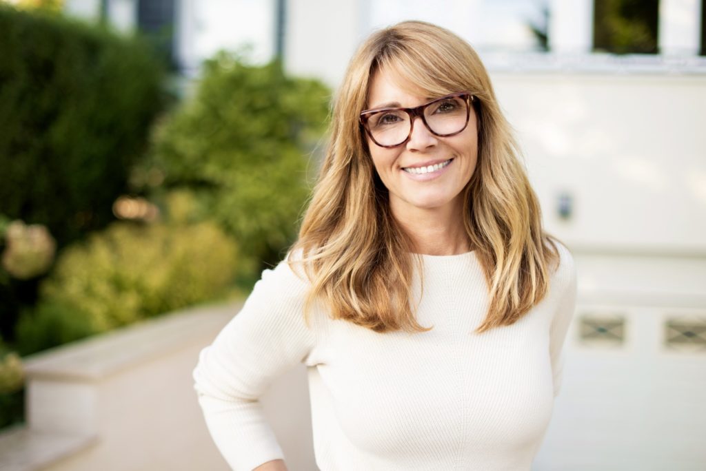 Mature woman with glasses smiling outside