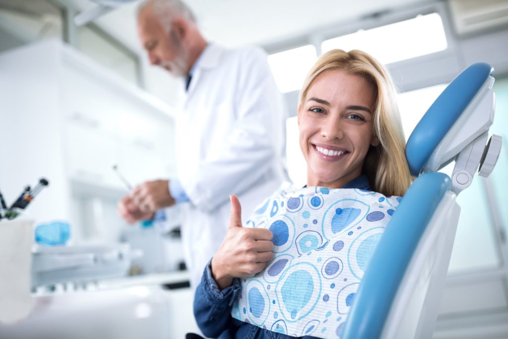 Woman smiling while giving thumbs up in dental chair