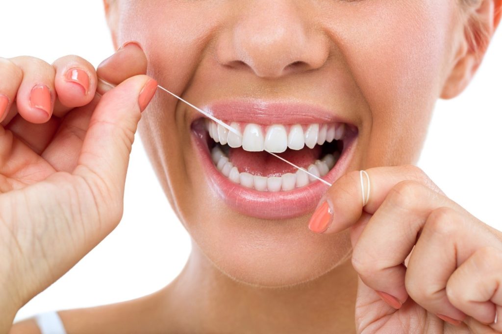 Closeup of woman smiling while flossing