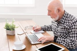 mature man writing on notepad