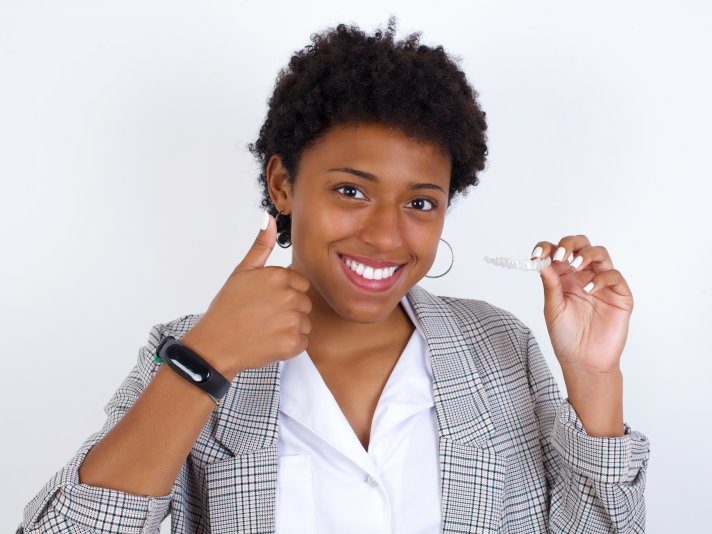 person holding ClearCorrect, giving thumbs up, and smiling