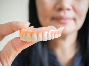 Woman holding dentures for the upper arch