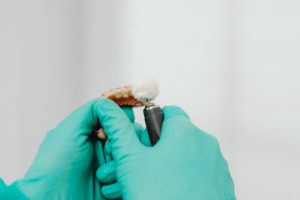 Gloved hands polishing a denture