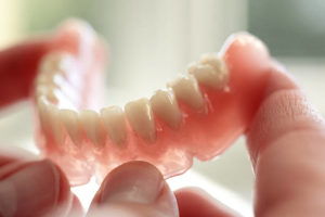 Close up of lower denture held in fingertips 