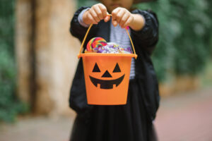 a child holding a jack-o-lantern Halloween bucket that's filled with candy