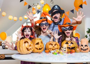 Woman, man, and two children in costumes behind table with candy and jack-o-lanterns